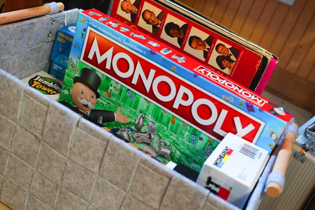 Box of board games including Monopoly and Jenga-style tumbling tower