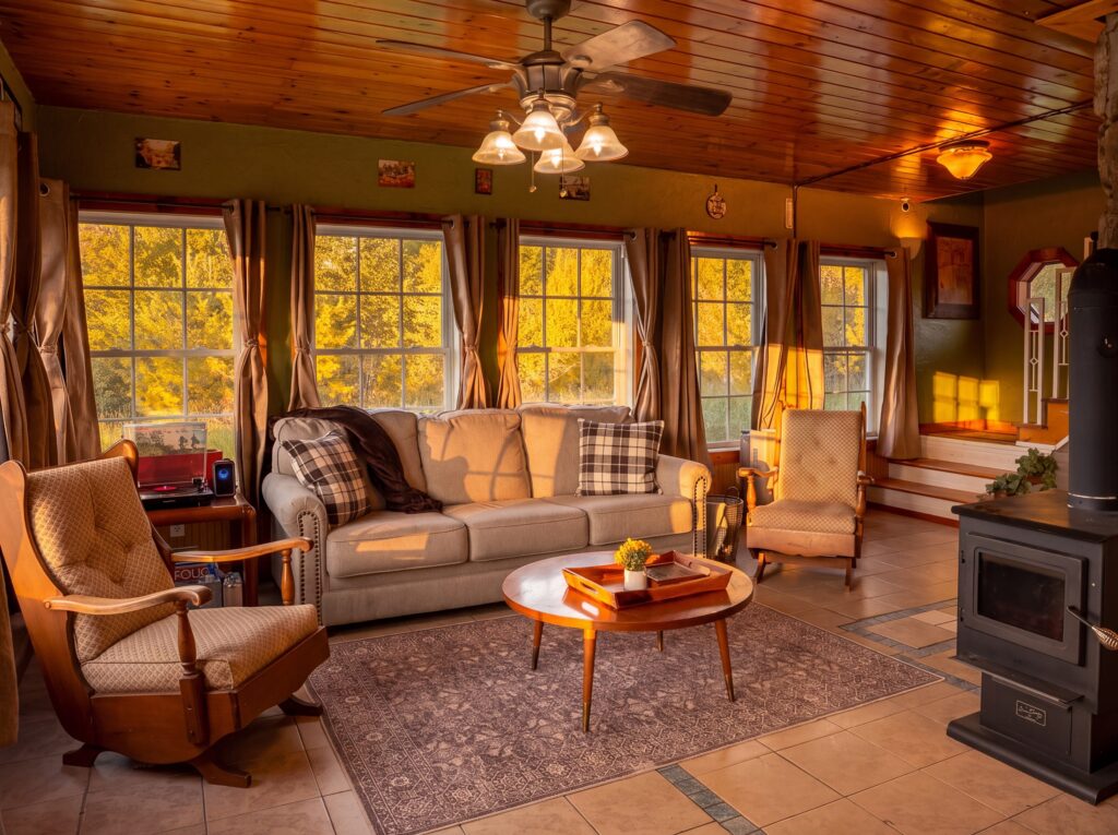Living room with a gray sofa, plaid pillows, a round wooden coffee table, and a black wood stove